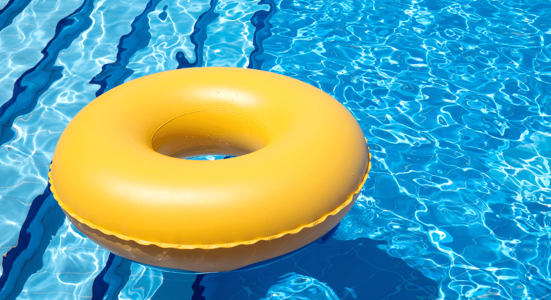 A yellow inflatable swim ring floats on the surface of a clear blue swimming pool.