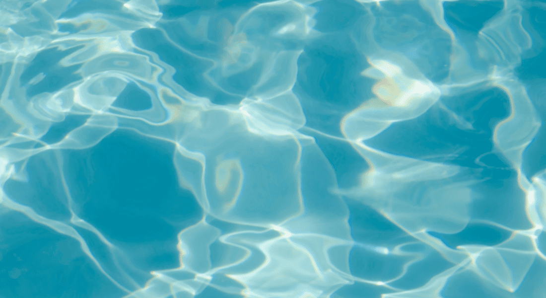 Sunlight reflects on the surface of clear blue water, creating shifting patterns and ripples.